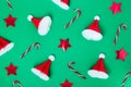 Creative christmas pattern background. Christmas candy canes, red stars and paper santa caps on a green background. New Royalty Free Stock Photo