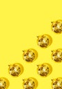 Creative Christmas pattern. Shiny gold disco balls over yellow background. Flat lay, top view. New year baubles with shining Royalty Free Stock Photo