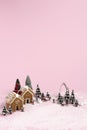 Creative Christmas scene made with with ginger houses, Santa Claus, trees, snow and reindeers on pink pastel color background Royalty Free Stock Photo