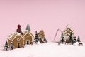 Creative Christmas scene made with with ginger houses, Santa Claus, trees, snow and reindeers on pink pastel color background Royalty Free Stock Photo