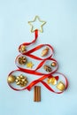 Creative Christmas tree made of gold decorations and red ribbon on light blue background. Christmas  winter  new year concept. Royalty Free Stock Photo