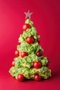 Creative christmas tree made of guacamole and cherry tomatoes on red background Royalty Free Stock Photo