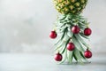 Creative Christmas tree made of pineapple and red bauble on grey concrete background, copy space. Greeting card, decoration for Royalty Free Stock Photo