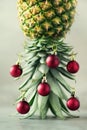 Creative Christmas tree made of pineapple and red bauble on grey concrete background, copy space. Greeting card, decoration for Royalty Free Stock Photo