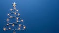 Creative Christmas tree shape made of glowing string lights and a silver star on a bold blue background perfect for Christmas and Royalty Free Stock Photo