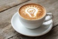 Creative coffee art with a glowing lightbulb design in a white cup on a rustic wooden table Royalty Free Stock Photo