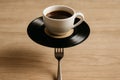 Creative coffee cup resting on a vinyl record with a fork balance at a modern cafe setting Royalty Free Stock Photo