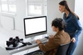 Creative collaboration concept. Photographer and his female assistant checking and discussing photos on computer, mockup Royalty Free Stock Photo