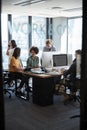 Creative colleagues in working in a casual office, seen through glass wall with text on it, vertical