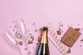 Creative composition with bottle of a champagne, two champagne glasses, gold baubles and confetti on pink background