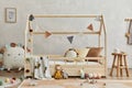 Creative composition of cozy scandi child`s room interior with wooden bed, plush and wooden toys and textile. Royalty Free Stock Photo