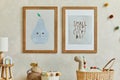 Creative composition of cozy scandinavian child`s room interior with two mock up poster frames, rattan basket, lamp, plush.