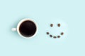 Creative composition: good morning or I love coffee. White cup with black coffee espresso and smile made from beans on blue Royalty Free Stock Photo