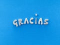 Gracias, thank you in spanish language composed with handmade wooden letters over blue color