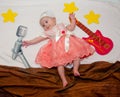 Creative composition. Little baby girl laying near drawn guitar, microphone and stars Royalty Free Stock Photo