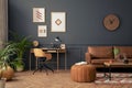Creative composition of living room interior with mock up poster frame, brown sofa, wooden desk, stylish armchair, pouf , coffee