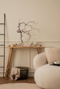 Creative composition of living room interior with wooden bench, white sofa, glass vase with branch, black basket, beige plaid, Royalty Free Stock Photo