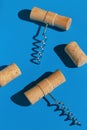 Creative composition made of corkscrews and wine bottle corks on blue background with shadow at sunlight. Party drink concept. Royalty Free Stock Photo