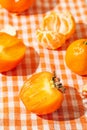 Creative composition made of fresh orange persimmon and tangerin fruits on cage cloth. Healthy food concept. Summer picnic idea Royalty Free Stock Photo