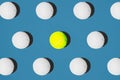 Creative composition made with yellow tennis ball and white balls on blue background.