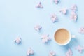 Creative composition with morning coffee and pink flowers on blue pastel background top view. Flat lay style.