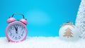 Creative composition with a pink alarm clock and Christmas bauble on snow. Minimal Christmas or New Year concept Royalty Free Stock Photo