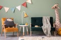 Creative composition of stylish and cozy child room interior design with greeen wall, plush toys, furniture and accessories. Royalty Free Stock Photo