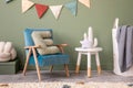 Creative composition of stylish and cozy child room interior design with green wall, plush toys, bright carpet, blue armchair,