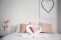 Creative composition with swans made of white terry towels on bed indoors