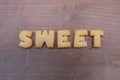 Sweet word composed with biscuit letters over a wooden board