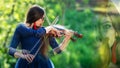 Creative composition. Young woman playing the violin at park. Shallow depth of field - image