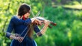 Creative composition. Young woman playing the violin at park. Shallow depth of field - image