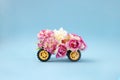 Creative concept of car made of fresh Spring flowers. Pink roses on yellow tires. Wedding ride..Pastel blue background Royalty Free Stock Photo