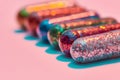 Creative concept with colorful glitter pills lying in a row isolated on pastel pink background. Minimal style, art Royalty Free Stock Photo
