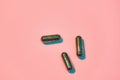 Creative concept with green glitter pills isolated on pastel pink background. Minimal style, art concept Royalty Free Stock Photo