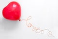 Creative concept. Hand holding red heart shape balloon with Love word from thread on white wooden background. Flat lay. Top view. Royalty Free Stock Photo
