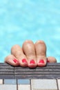 Hold on. Closeup of red painted finger nails on the side of a pool. Royalty Free Stock Photo