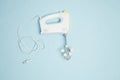 Creative concept made of white electric hand mixer with beaters, cabel and white rose flowers on pastel blue background. Household Royalty Free Stock Photo