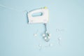 Creative concept made of white electric hand mixer with beaters and white rose flowers on pastel blue background. Household Royalty Free Stock Photo