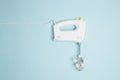 Creative concept made of white electric hand mixer with beaters and white rose flowers on pastel blue background. Household Royalty Free Stock Photo