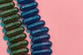 Creative concept with many green and blue glitter pills lying in two rows isolated on pastel pink background. Minimal Royalty Free Stock Photo