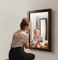 Creative conceptual collage. Young woman looking in mirror and seeing her little self. Back to childhood memories Royalty Free Stock Photo