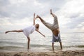 Creative couple relaxing on the ocean beach. A man and a woman do somersaults and jumps in the water. The concept of unusual