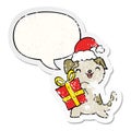 A creative cute cartoon puppy and christmas present and hat and speech bubble distressed sticker Royalty Free Stock Photo