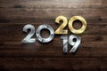 Creative design, Happy New Year, Metallic and gold numbers. Year 2019 is changing to 2020 Design on a wooden background. Merry Royalty Free Stock Photo