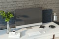 Creative designer desktop with empty computer monitor, lamp, supplies and other items. Black brick wall background. Royalty Free Stock Photo