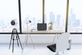 Creative designer desktop with empty laptop computer in modern interior with camera, window and bright city view. Royalty Free Stock Photo