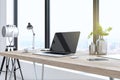 Creative designer desktop with empty laptop computer in modern interior with camera, window and bright city view. Mock up, 3D Royalty Free Stock Photo