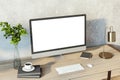 Creative designer desktop with empty white computer monitor, lamp, supplies and other items. Concrete wall background. Mock up, 3D Royalty Free Stock Photo