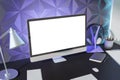 Creative designer desktop with empty white mock up computer display, various items and decorative purple wall in the background. Royalty Free Stock Photo